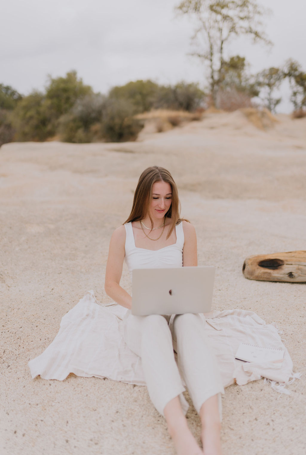Kendra from Covarra Studio is working on her computer at the beach.