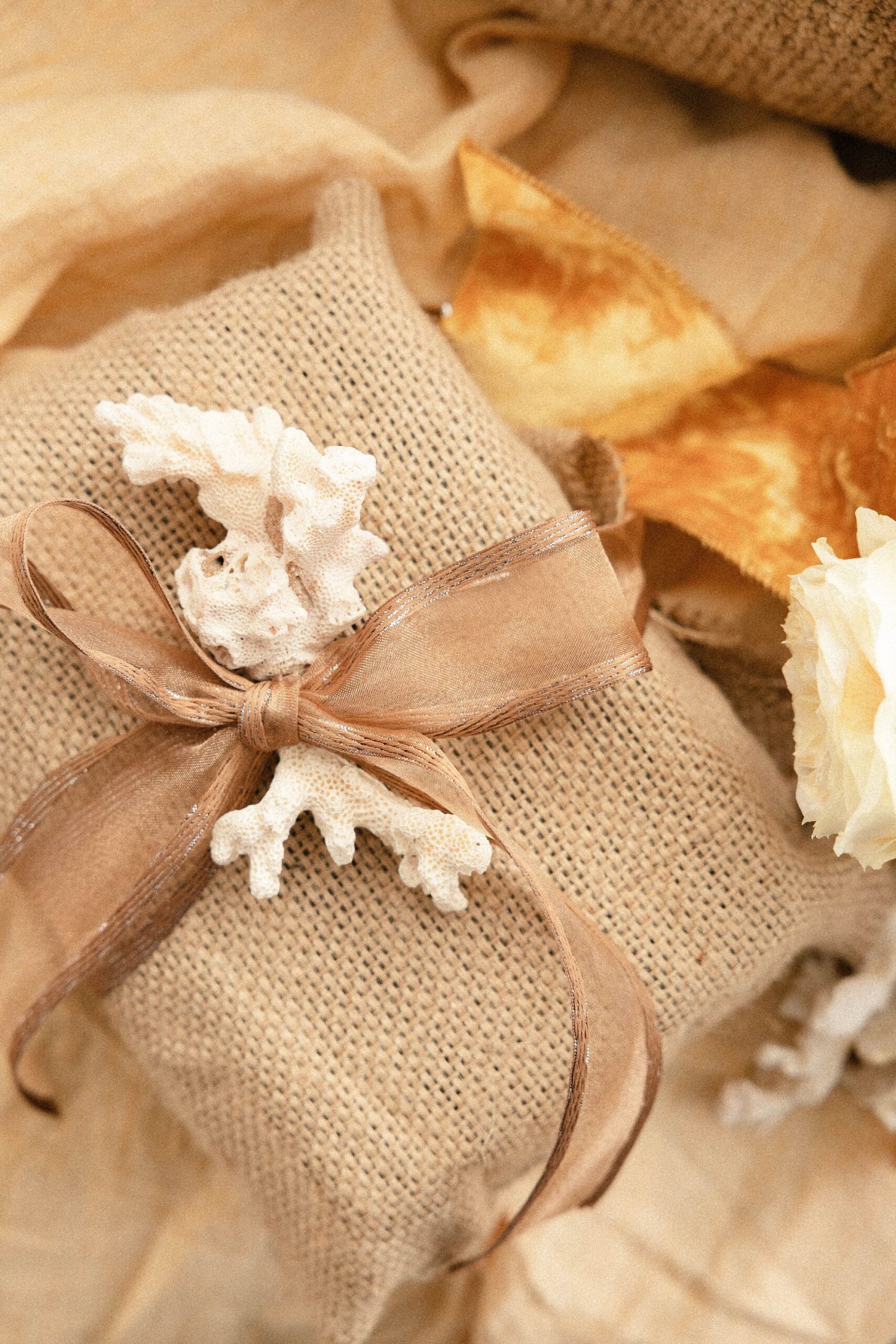 a gift wrapped in burlap and topped with a bow and seashell